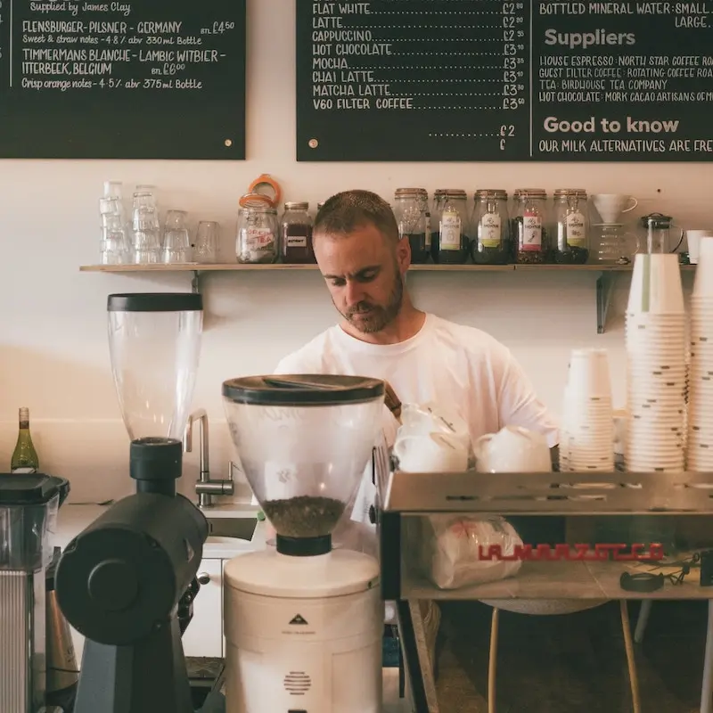 A man in a bar making coffee with a machine.