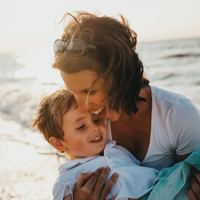 A mother and a son hugging each other at the beach.