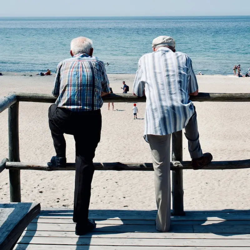 Two old men standing at the front of beach looking at the panorama.